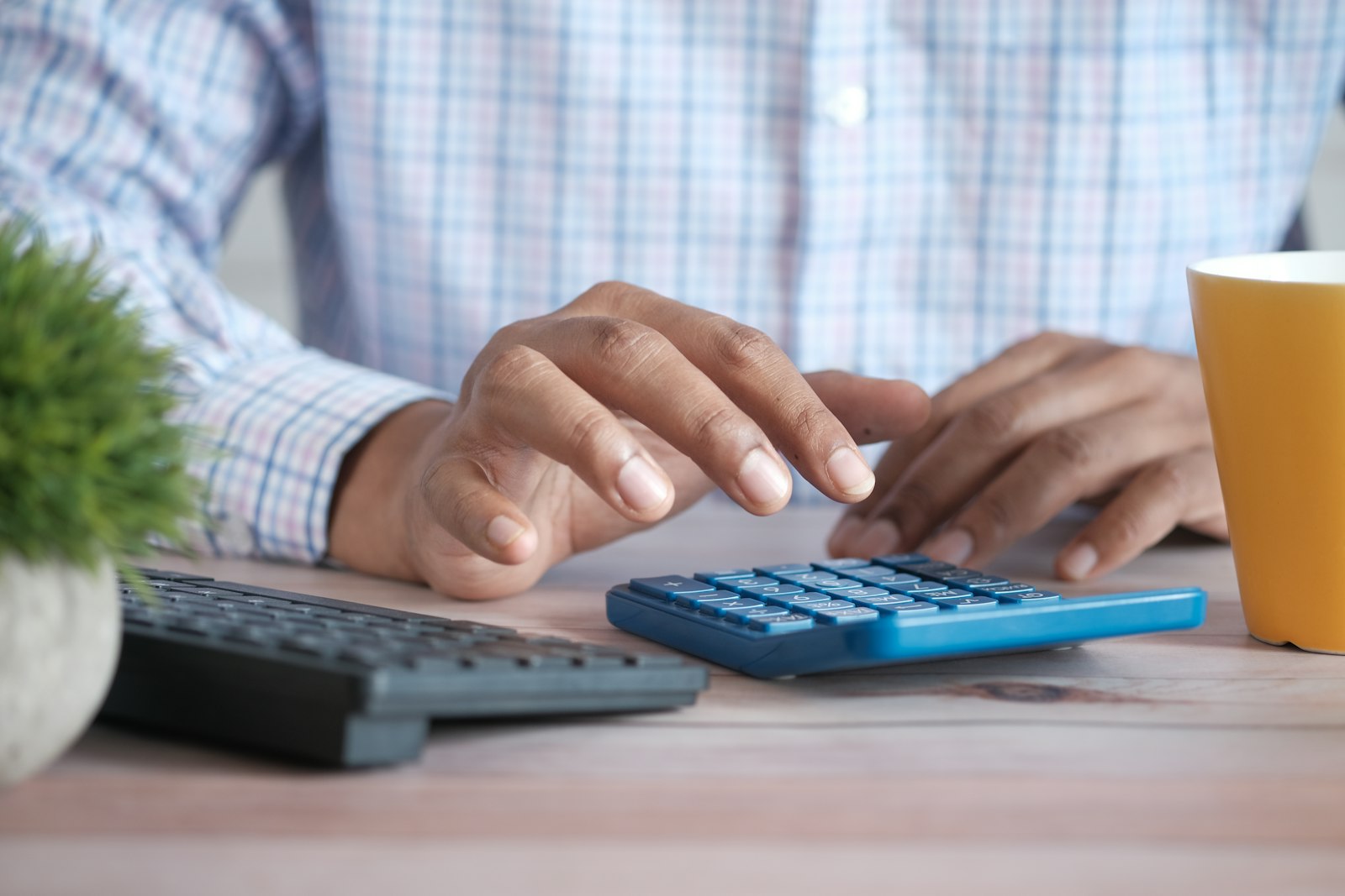 A person working out costs on a blue calculator at a desk