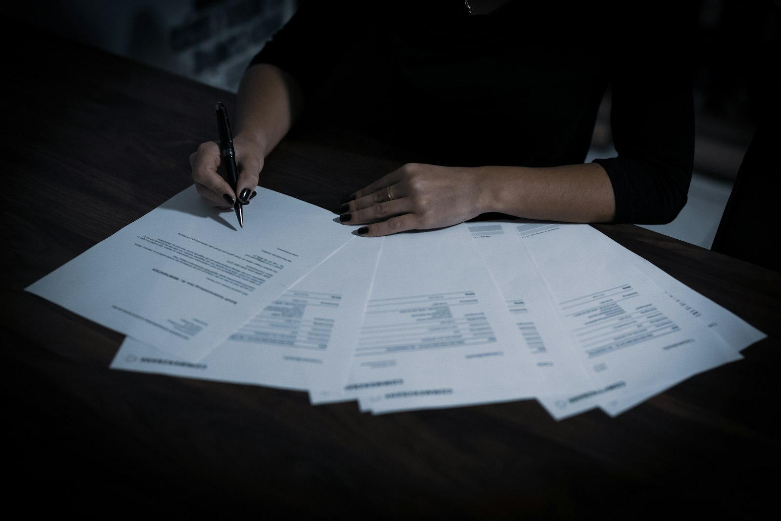 A woman sitting at a table covered in papers, working through an application